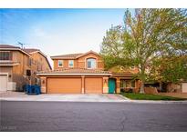 Two-story home featuring a three car garage and a well manicured front lawn with mature landscaping at 1017 Fairbury St, Henderson, NV 89052