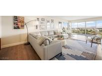 Open-concept living room featuring a gray sectional sofa, stylish decor, and sliding doors leading to a balcony with a view at 3111 Bel Air Dr # 10F, Las Vegas, NV 89109