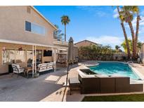 Inviting backyard features a sparkling pool, spa, and covered patio with comfortable seating under a blue sky at 1708 Crest Ave, Las Vegas, NV 89119