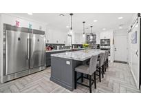 Bright, open kitchen featuring a large island with marble countertop, pendant lighting, and stainless steel appliances at 6995 Rogers St, Las Vegas, NV 89118