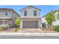 Charming stucco home featuring a two-car garage, brick driveway, and manicured landscaping at 406 Misterioso St, Henderson, NV 89011