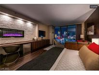 Modern bedroom featuring a fireplace, wooden floors and breathtaking city views through large windows at 4381 W Flamingo Rd # 24304, Las Vegas, NV 89103