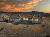 Charming single-story home with a three-car garage, desert landscaping, and mountain views at sunset at 6101 Cavalry Trl, Pahrump, NV 89060