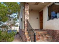 Welcoming front porch with brick accents and a wrought-iron railing provides a charming entry to the home at 664 Sky Rd, Indian Springs, NV 89018