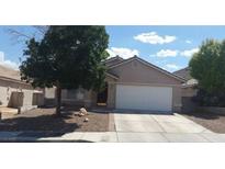 Tan single-story home with a two car garage, desert landscaping and mature shade tree in the front yard at 33 Newburg Ave, North Las Vegas, NV 89032