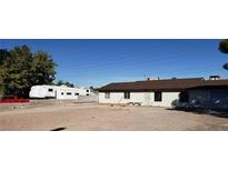 A spacious lot with a white home, some trees, and an RV parked on the side at 7990 Firethorn, Las Vegas, NV 89123