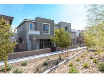A modern two-story home with a desert-landscaped front yard, a gray exterior and a stone accent wall at 11756 Emerald Lake Ave, Las Vegas, NV 89138