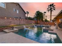 Beautiful backyard pool featuring waterfalls, fire pits, and lush landscaping, perfect for outdoor relaxation and entertaining at 1283 Peppercorn Ave, Henderson, NV 89012