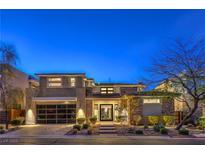 Contemporary two-story home with a stone and stucco facade and a glass-paneled garage door at twilight at 10 Sugarberry Ln, Las Vegas, NV 89135