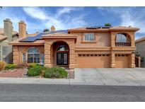 Two-story home with a three-car garage, an arched entryway, a tile roof, solar panels, and desert landscaping at 8716 Castle Hill Ave, Las Vegas, NV 89129