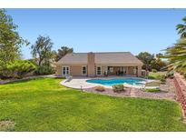 Inviting backyard features a sparkling pool, lush green lawn, and a charming patio area perfect for outdoor relaxation at 5725 Owl Butte Ct, Las Vegas, NV 89149
