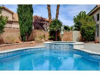 Sparkling blue swimming pool and spa with waterfall feature surrounded by lush landscaping at 2401 Rice Flower Cir, Las Vegas, NV 89134