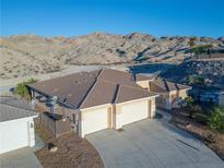 Stunning exterior view with a three-car garage and a mountain backdrop at 3439 Cottage Canyon St, Laughlin, NV 89029