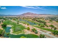 Scenic aerial view of lush golf course with mature trees, serene ponds, and mountain backdrop on a sunny day at 6076 Wheat Penny Ave, Las Vegas, NV 89122
