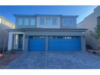 Two-story home featuring a gray exterior and a striking blue two-car garage door, complemented by a paved driveway at 629 Soaring Wings Ave, Las Vegas, NV 89183