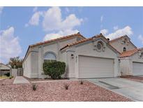 Charming home featuring a two-car garage, stucco exterior, and red rock landscaping at 8121 Heavenly Star Cir, Las Vegas, NV 89128