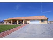 Charming single-story home featuring a vibrant lawn, long driveway, and a terracotta-colored tiled roof at 3110 National Ave, Pahrump, NV 89048
