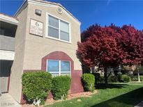 Two-story condo featuring manicured landscaping and red tree at 5055 W Hacienda Ave # 2055, Las Vegas, NV 89118