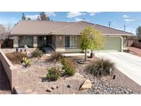 Landscaped front yard featuring desert landscaping, a light brown exterior, and a tile roof under a bright, blue sky at 5481 Lincolnwood Ct, Pahrump, NV 89061