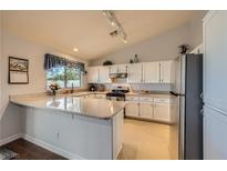 Bright kitchen features white cabinetry, granite counters, track lighting, and a breakfast bar at 1022 Atticus Ave, Henderson, NV 89015