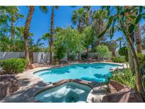 Backyard pool and hot tub surrounded by lush greenery and palm trees at 2812 Shadow Creek Cir, Las Vegas, NV 89117