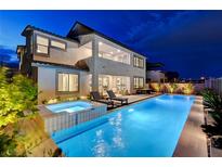 An outdoor pool and hot tub are surrounded by lounge chairs in the backyard of this well-lit home at 472 Windstone Crest Ave, Las Vegas, NV 89138