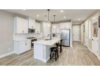 Bright kitchen features a large island with bar seating and modern stainless steel appliances at 712 Monroe Hill Pl, Henderson, NV 89011
