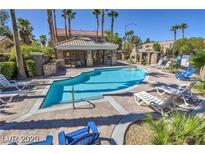 Community pool area with lounge chairs, a covered area and lush landscaping at 6790 Gold Yarrow St, Las Vegas, NV 89148