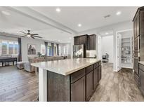 Open-concept kitchen with large island, wood floors, stainless appliances, and view to the living area at 8245 Broad Branch Way, Las Vegas, NV 89113