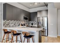 Modern kitchen features a breakfast bar, stainless steel appliances, sleek countertops, and stylish backsplash at 353 E Bonneville Ave # 754, Las Vegas, NV 89101