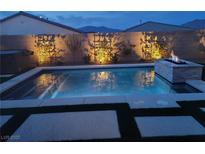 Beautiful backyard pool with a stone fire pit feature and decorative wall at 9974 Petroglyph Canyon Ave, Las Vegas, NV 89166