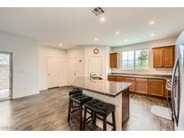 Open kitchen with island, granite countertops, wooden cabinets, and stainless steel appliances at 10663 Sariah Skye Ave, Las Vegas, NV 89166