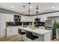 Bright kitchen featuring white cabinets, quartz countertops, black backsplash, and stainless steel appliances at 1660 Izabella Ave, Las Vegas, NV 89169