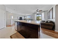 Modern kitchen island featuring a built-in sink, dark cabinetry, and lots of room for entertaining at 9121 Ripple Ridge Ave # 101, Las Vegas, NV 89149