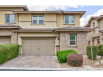 Inviting townhome with a two-car garage, manicured landscaping, and brick accents at 10356 Addie De Mar Ln, Las Vegas, NV 89135