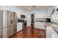Bright kitchen featuring stainless steel appliances, granite countertops, white cabinets, and hardwood floors at 5010 Mick Pl, Las Vegas, NV 89103