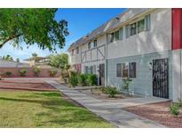 Charming townhome featuring a well-maintained lawn and quaint landscaping at 609 Greenbriar Townhouse Way, Las Vegas, NV 89121