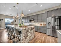 Modern kitchen featuring a large island with granite countertop, stainless steel appliances, and gray cabinetry at 19 Hilltop Crest St, Henderson, NV 89011