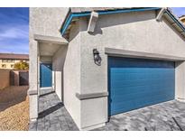 Modern home showcasing a blue garage door and door with complementary hardscaping and stucco at 6164 Violet Falls St # 44, North Las Vegas, NV 89081
