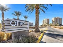 Exterior view of community sign featuring landscaping, palm trees, and luxury high rise condos in the background at 8255 Las Vegas Blvd # 1315, Las Vegas, NV 89123