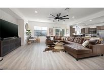 Expansive open living room with large sectional sofa, modern ceiling fan, and seamless flow to the kitchen at 11913 Alava Ave, Las Vegas, NV 89138