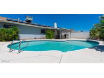 A backyard pool surrounded by lush landscaping and a covered patio area perfect for outdoor relaxation and entertaining at 6361 W Viking Rd, Las Vegas, NV 89103