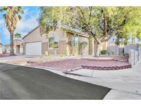 Tan single story home with a white garage door, desert landscaping and a large shade tree in the front yard at 7909 Smokey Ridge Ct, Las Vegas, NV 89131