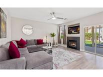 Bright living room featuring a gray sectional sofa, fireplace, modern ceiling fan, and sliding glass door to patio at 191 Reed Ln, Henderson, NV 89074