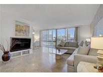 Bright living room featuring a comfortable sofa, marble floors, and city views through large windows at 205 E Harmon Ave # 306, Las Vegas, NV 89169