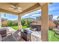 Inviting covered patio with ceiling fan, hot tub, and a cozy fire pit area with beautiful pavers at 415 Carsin Wayne Ct, North Las Vegas, NV 89031