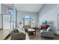 Bright living room with vaulted ceilings, large windows, and comfortable seating arrangement at 9709 Terrace Green Ave, Las Vegas, NV 89117