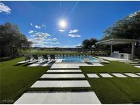 A backyard pool is surrounded by lush landscaping and offers picturesque golf course views at 5 Clear Crossing Trl, Henderson, NV 89052
