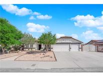 Charming single-story home featuring a three car garage, desert landscaping and a tile roof at 6150 W Brooks Ave, Las Vegas, NV 89108
