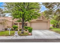 Tan home features a two-car garage, mature tree, and a well-manicured front yard at 8513 Glenmount Dr, Las Vegas, NV 89134